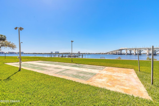 view of community featuring a lawn, shuffleboard, and a water view