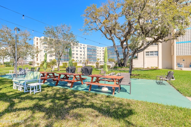 view of property's community featuring a patio and a lawn