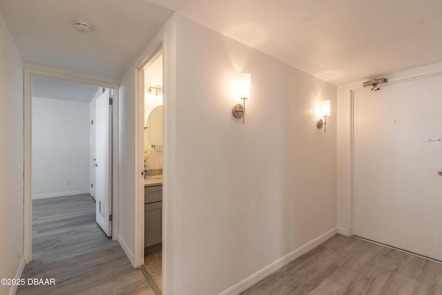 hall featuring baseboards and light wood-type flooring