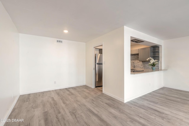 empty room with light wood-type flooring, baseboards, and visible vents