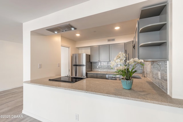 kitchen with light stone countertops, visible vents, open shelves, gray cabinetry, and stainless steel appliances