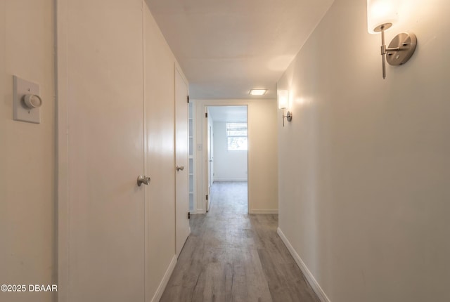 hallway featuring light wood-type flooring and baseboards