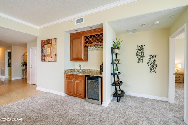 3801 S Atlantic Ave Unit 303, Daytona Beach Shores, FL 32118 - indoor wet bar featuring wine cooler, light colored carpet, crown molding, a textured ceiling, and baseboards