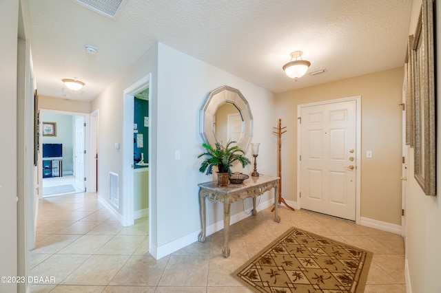 entryway with a textured ceiling and light tile patterned floors