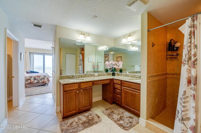 3801 S Atlantic Ave Unit 303, Daytona Beach Shores, FL 32118 - bathroom featuring tile patterned flooring, a tile shower, double vanity, ensuite bathroom, and a textured ceiling
