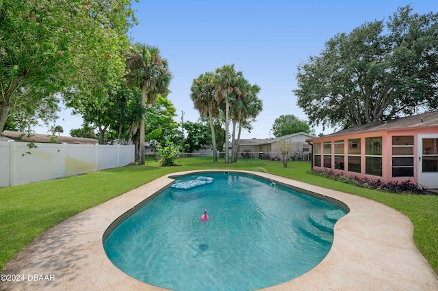 view of swimming pool featuring a lawn and a sunroom