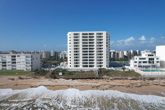 view of building exterior with a beach view and a water view