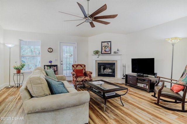 living room with vaulted ceiling, ceiling fan, light hardwood / wood-style floors, and a tile fireplace