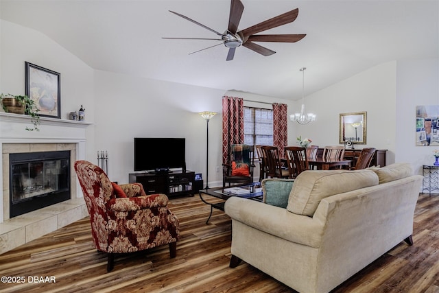 living room featuring hardwood / wood-style flooring, vaulted ceiling, ceiling fan with notable chandelier, and a fireplace