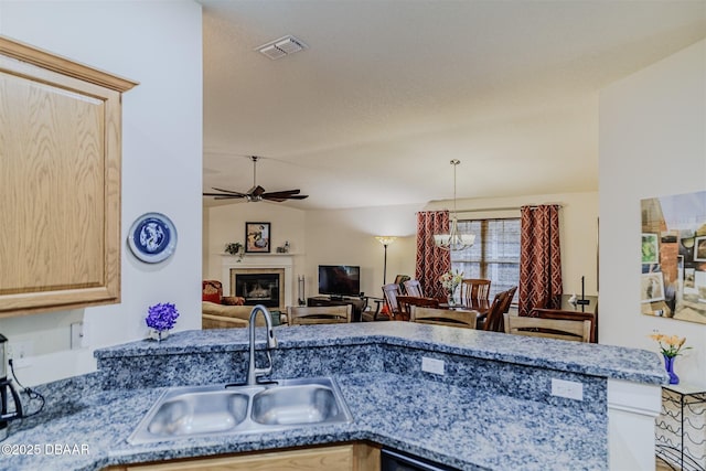 kitchen featuring lofted ceiling, light brown cabinetry, sink, kitchen peninsula, and ceiling fan with notable chandelier