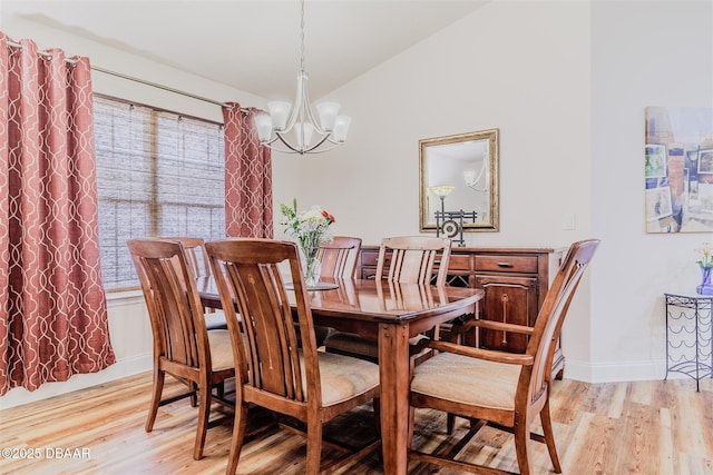 dining area with light hardwood / wood-style floors, a chandelier, and vaulted ceiling