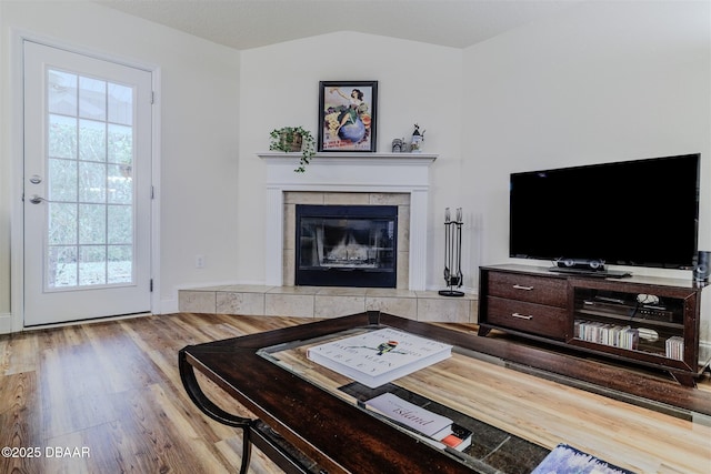 living room featuring lofted ceiling, hardwood / wood-style flooring, and a fireplace