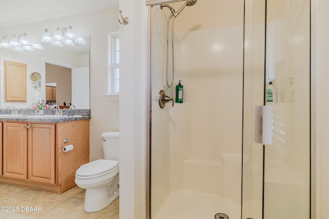 bathroom featuring toilet, vanity, and a shower with shower door