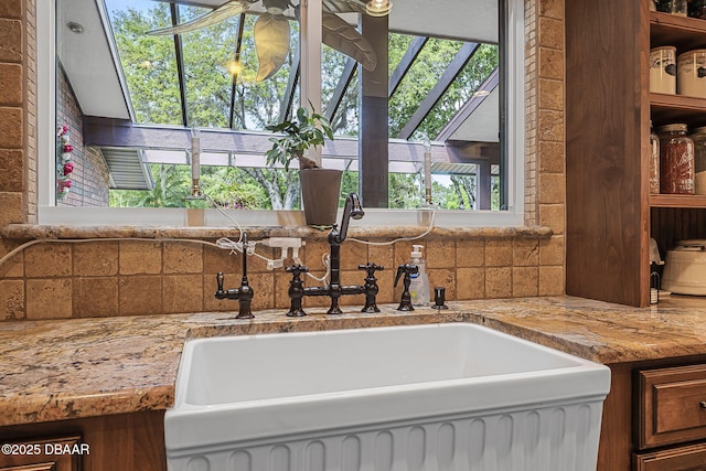 229 Riverbend Rd, Ormond Beach, FL 32174 - kitchen view of a sink, decorative backsplash, ceiling fan, light stone countertops, and brown cabinets