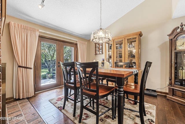 229 Riverbend Rd, Ormond Beach, FL 32174 - dining room with vaulted ceiling, hardwood / wood-style flooring, a textured ceiling, a chandelier, and french doors
