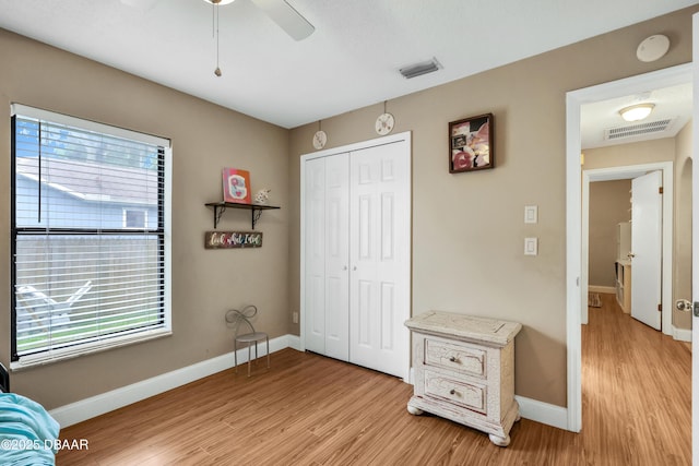 bedroom with multiple windows, a closet, light wood-type flooring, and ceiling fan