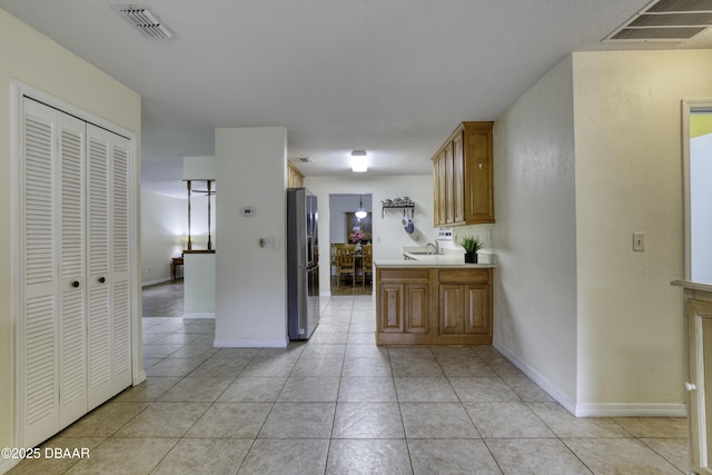 kitchen featuring light tile patterned floors, visible vents, light countertops, and stainless steel fridge with ice dispenser