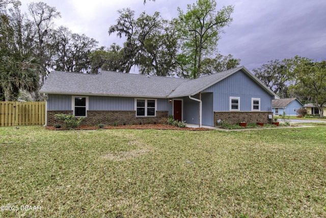 ranch-style house featuring a front lawn, fence, brick siding, and roof with shingles