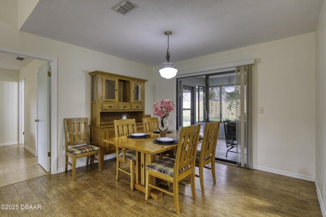 dining space with visible vents, baseboards, and wood finished floors