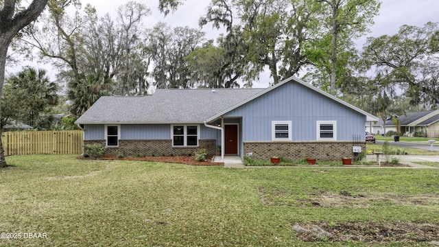 ranch-style house with brick siding, roof with shingles, a front yard, and fence