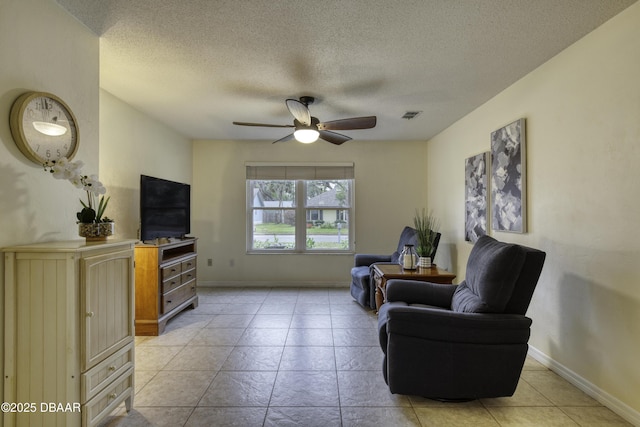 living room featuring visible vents, baseboards, ceiling fan, light tile patterned flooring, and a textured ceiling