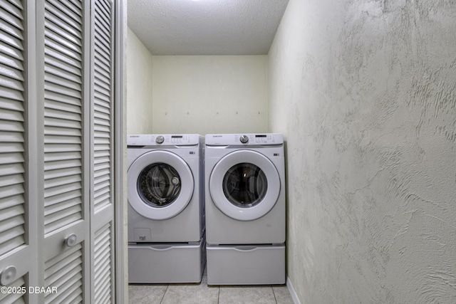 washroom featuring a textured ceiling, washing machine and dryer, tile patterned flooring, laundry area, and a textured wall