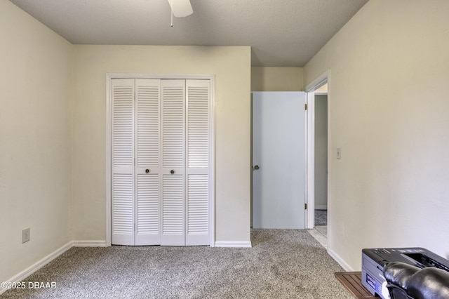 unfurnished bedroom featuring baseboards, carpet, a closet, and a textured ceiling