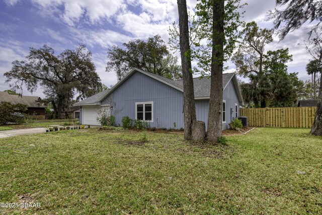 view of side of property with central air condition unit, a yard, and fence