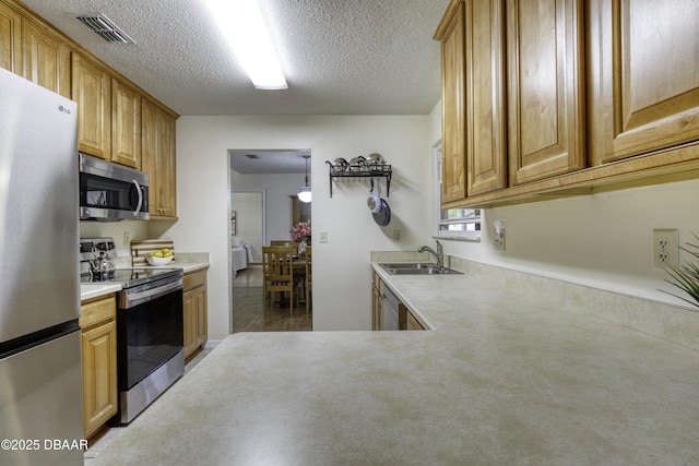 kitchen featuring visible vents, a sink, light countertops, appliances with stainless steel finishes, and a textured ceiling