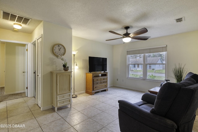 living room featuring light tile patterned floors, a ceiling fan, visible vents, and baseboards