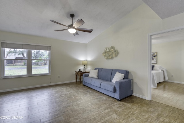 living room featuring baseboards, wood finished floors, ceiling fan, and vaulted ceiling