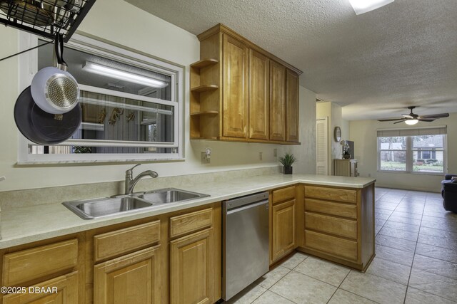 kitchen with a peninsula, a sink, a textured ceiling, stainless steel dishwasher, and open floor plan