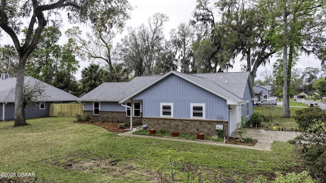 ranch-style home featuring brick siding, a shingled roof, a front lawn, and fence