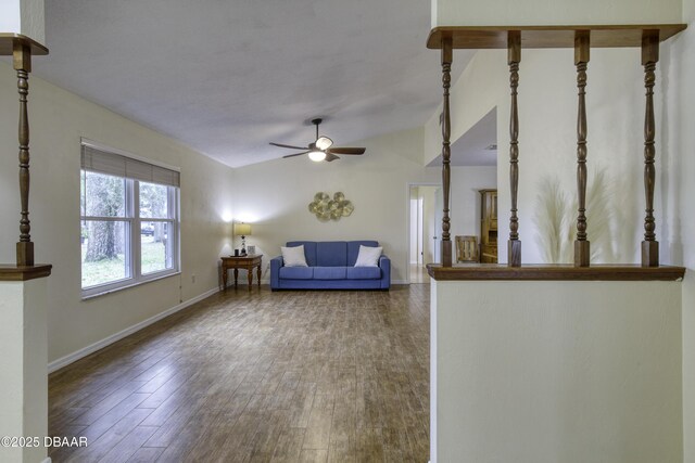 unfurnished living room with lofted ceiling, wood finished floors, baseboards, and ceiling fan