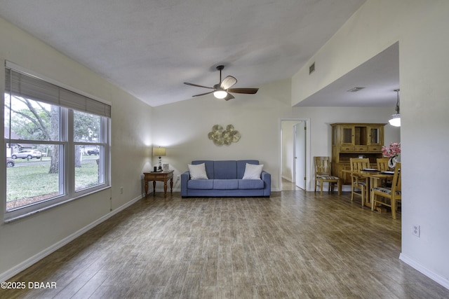 living area featuring visible vents, ceiling fan, baseboards, lofted ceiling, and wood finished floors