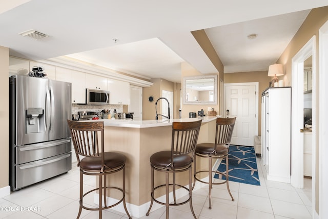 kitchen with light tile patterned flooring, white cabinetry, appliances with stainless steel finishes, backsplash, and sink