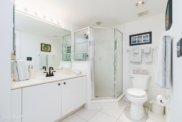 bathroom featuring toilet, vanity, tile patterned flooring, and a shower with door