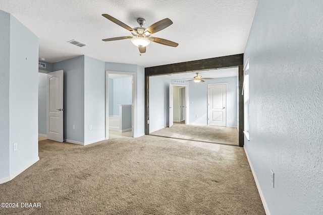 carpeted spare room featuring beam ceiling, ceiling fan, and a textured ceiling