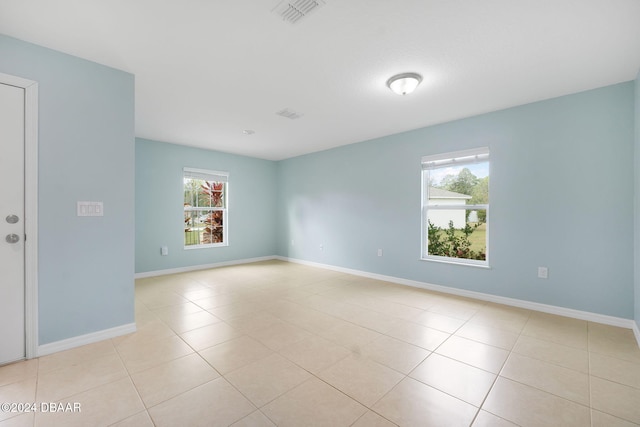empty room with light tile patterned floors and a healthy amount of sunlight