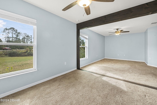 carpeted empty room with ceiling fan and beam ceiling