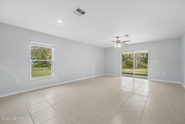 tiled spare room featuring a textured ceiling, ceiling fan, and a healthy amount of sunlight