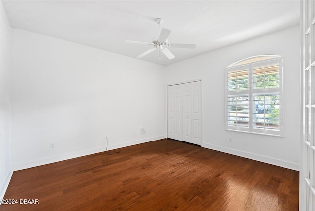 unfurnished bedroom featuring ceiling fan, dark wood-type flooring, and a closet