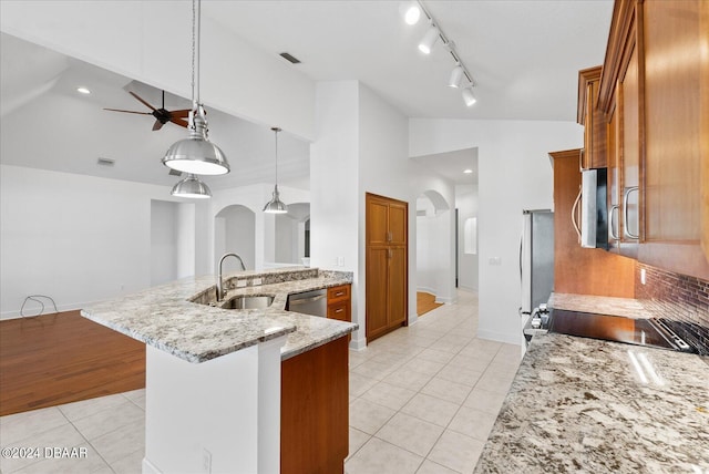 kitchen with sink, decorative light fixtures, light stone countertops, light tile patterned flooring, and stainless steel appliances