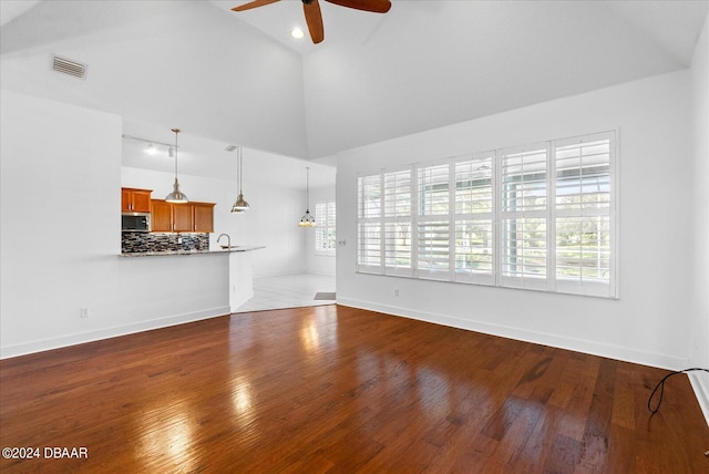 unfurnished living room with hardwood / wood-style flooring, high vaulted ceiling, and ceiling fan