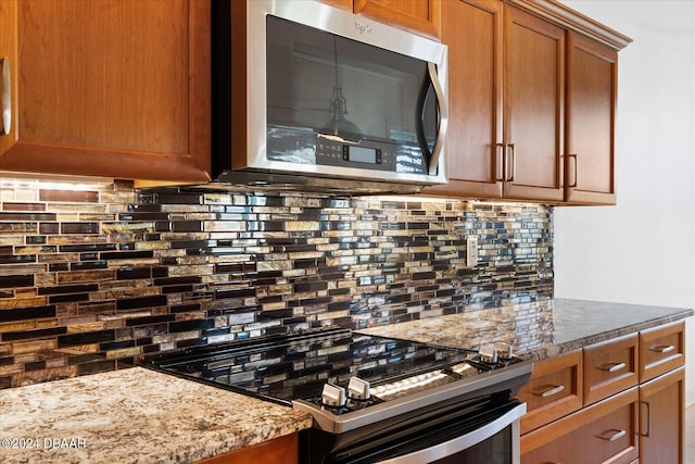 kitchen with backsplash, light stone countertops, and appliances with stainless steel finishes