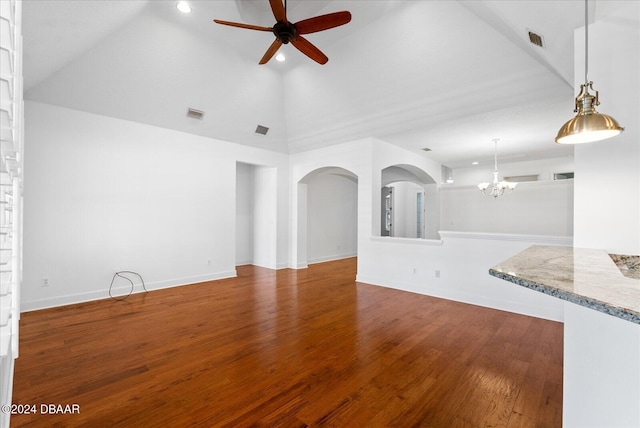 unfurnished living room with ceiling fan with notable chandelier, dark hardwood / wood-style floors, and high vaulted ceiling