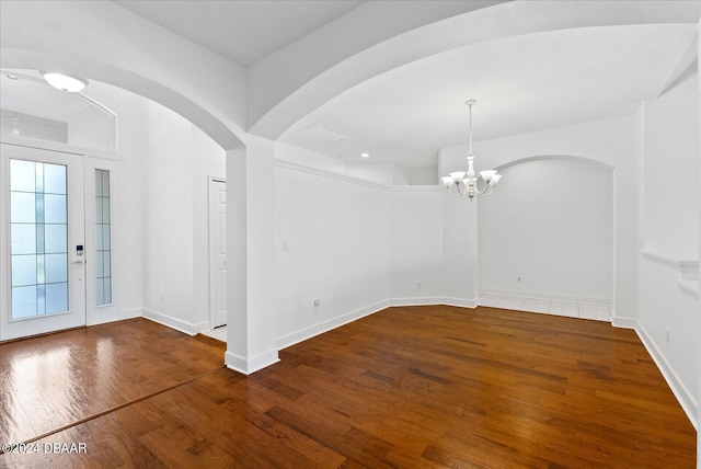 empty room featuring dark wood-type flooring and an inviting chandelier