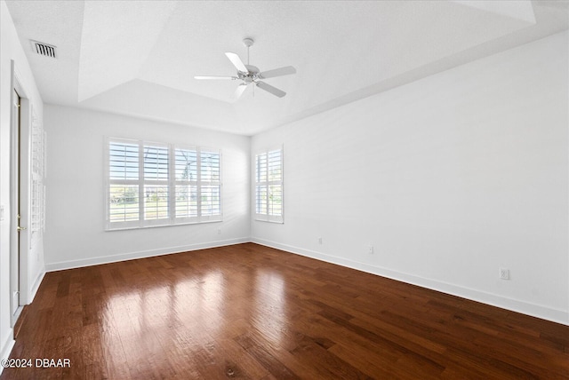 empty room featuring ceiling fan, dark hardwood / wood-style flooring, and a raised ceiling