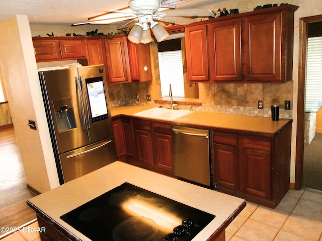 kitchen with sink, light tile patterned floors, ceiling fan, appliances with stainless steel finishes, and backsplash