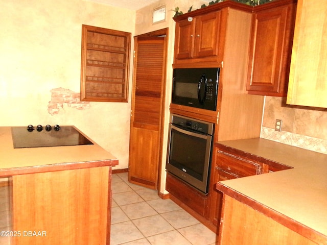 kitchen featuring backsplash, light tile patterned floors, and black appliances